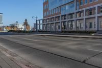 an empty city street and large buildings in the background as seen from the side of the road