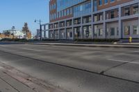 an empty city street and large buildings in the background as seen from the side of the road