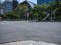 an empty city street has trees and tall buildings in the distance and a red fire hydrant in the middle of the street