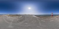 a fish - eye lens shows an empty asphalt street and the sun in the background