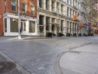 empty cobbled city street in front of some tall buildings with a building sign and a bench