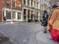 empty cobbled city street in front of some tall buildings with a building sign and a bench