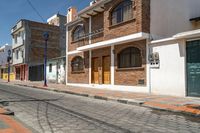 an empty cobblestone street with brick buildings and wooden doors that are open on each side