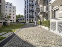 an empty cobblestone street between two multi -story buildings in a city