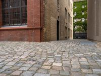 two empty cobblestones along an alley of a small town building with a clock on top