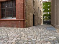 two empty cobblestones along an alley of a small town building with a clock on top