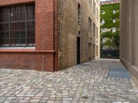 two empty cobblestones along an alley of a small town building with a clock on top