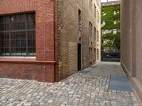 two empty cobblestones along an alley of a small town building with a clock on top