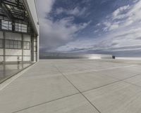 a view of an empty commercial airplane tarmac by the ocean with dramatic clouds behind