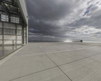 a view of an empty commercial airplane tarmac by the ocean with dramatic clouds behind