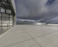 a view of an empty commercial airplane tarmac by the ocean with dramatic clouds behind