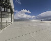 a view of an empty commercial airplane tarmac by the ocean with dramatic clouds behind