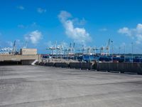 empty commercial parking lot with boats in distance on sunny day with blue sky and clouds