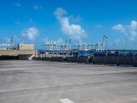 empty commercial parking lot with boats in distance on sunny day with blue sky and clouds