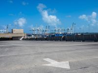 empty commercial parking lot with boats in distance on sunny day with blue sky and clouds