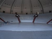 an empty concert auditorium with seating and two round seats, including a guitar stand and a desk