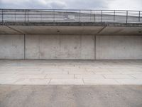 the empty concrete floor is next to the ceiling under a metal railing and fence above it