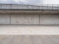 the empty concrete floor is next to the ceiling under a metal railing and fence above it