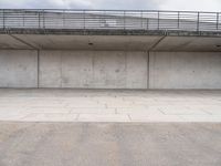 the empty concrete floor is next to the ceiling under a metal railing and fence above it