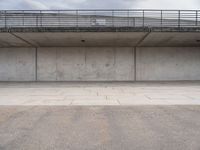 the empty concrete floor is next to the ceiling under a metal railing and fence above it