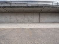 the empty concrete floor is next to the ceiling under a metal railing and fence above it