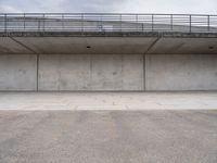 the empty concrete floor is next to the ceiling under a metal railing and fence above it