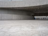 a building with cement roof near green grass and lawn in front of it, under a gray sky