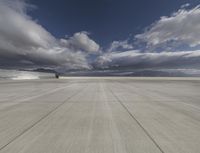 large empty concrete planes landing area under dark clouds in sky shotr and clouds above