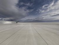 large empty concrete planes landing area under dark clouds in sky shotr and clouds above