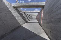 empty concrete ramp with sky and cloud in background, seen from inside the tunnel of a house