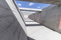 empty concrete ramp with sky and cloud in background, seen from inside the tunnel of a house