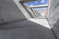 empty concrete ramp with sky and cloud in background, seen from inside the tunnel of a house