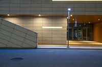 empty concrete stairs and large illuminated building entrance with stairs glowing in the dark at night