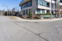 a corner parking lot that is empty with the building and street sign in front of it