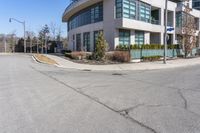 a corner parking lot that is empty with the building and street sign in front of it