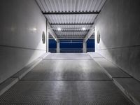 a white empty corridor at night with a bright blue sky in the background in a large metal storage building