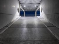 a white empty corridor at night with a bright blue sky in the background in a large metal storage building