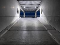 a white empty corridor at night with a bright blue sky in the background in a large metal storage building