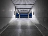 a white empty corridor at night with a bright blue sky in the background in a large metal storage building
