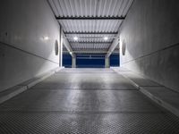 a white empty corridor at night with a bright blue sky in the background in a large metal storage building