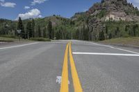 two yellow lines on an empty country road with mountains in the background on a sunny day