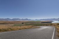 the road is empty on this big country road to nowhere in new zealand, with mountains in the distance