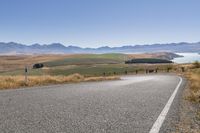 the road is empty on this big country road to nowhere in new zealand, with mountains in the distance