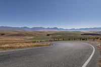 the road is empty on this big country road to nowhere in new zealand, with mountains in the distance