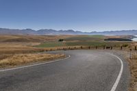 the road is empty on this big country road to nowhere in new zealand, with mountains in the distance