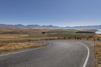 the road is empty on this big country road to nowhere in new zealand, with mountains in the distance