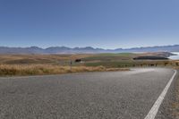 the road is empty on this big country road to nowhere in new zealand, with mountains in the distance