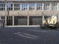 a view of an empty courtyard in the background is a window to an old factory with many glass windows