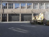 a view of an empty courtyard in the background is a window to an old factory with many glass windows