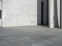 an empty courtyard with the doors open on a building side view of this building has a large wall with two vertical columns at one end and there is a hole in front